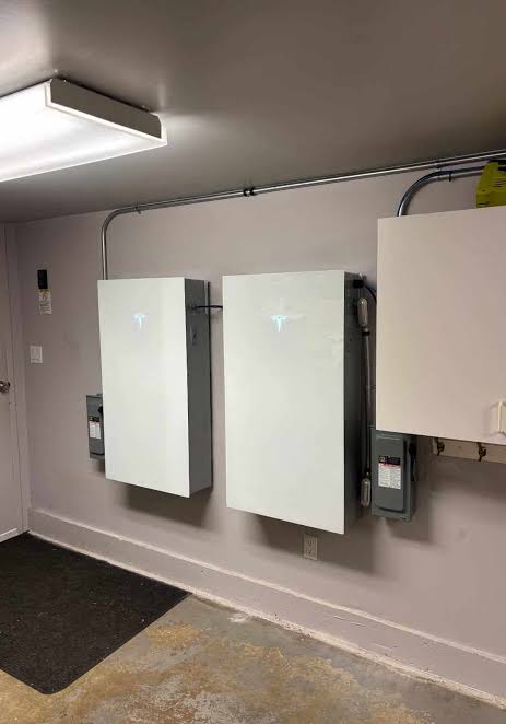 Two Tesla Powerwalls installed on a garage wall.