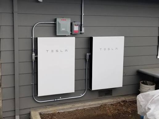 Two Tesla Powerwalls installed on a house wall.